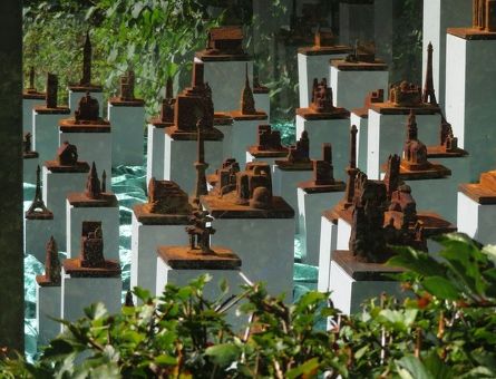 Viele kleine rostfarbene Häuschen auf weißen Säulen in einer Glasvitrine im Botanischen Garten Duisburg 2019